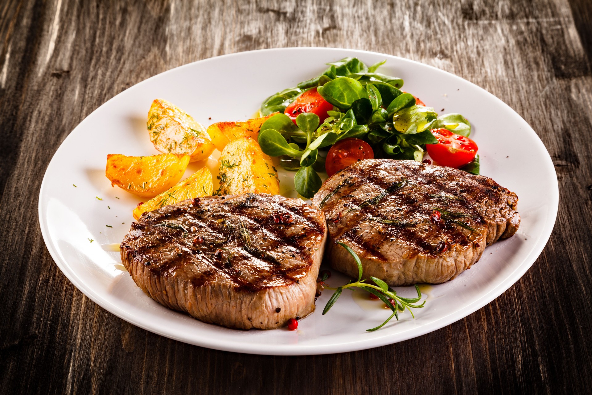 Beef steaks, baked potatoes and vegetable salad