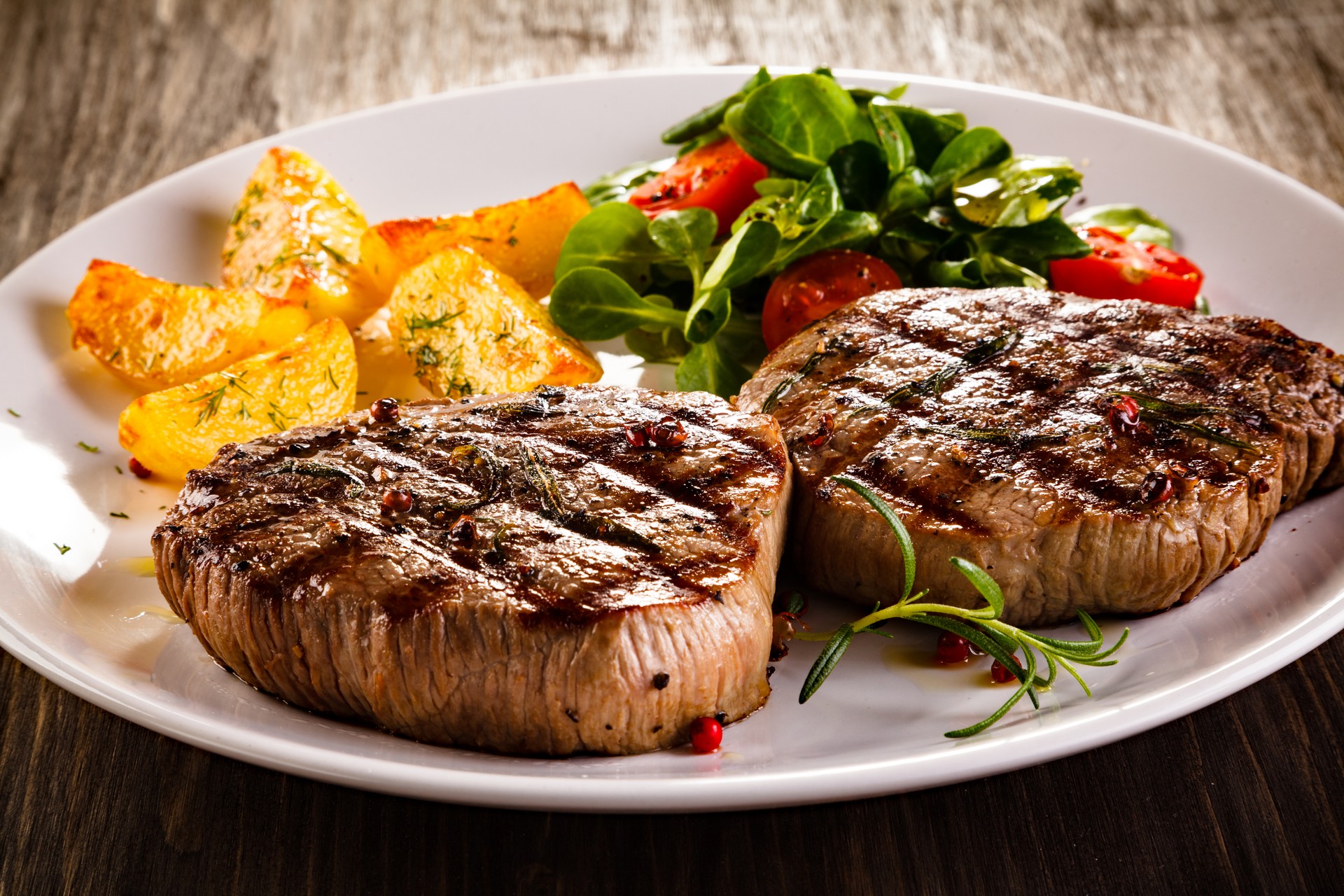 Beef steaks, baked potatoes and vegetable salad