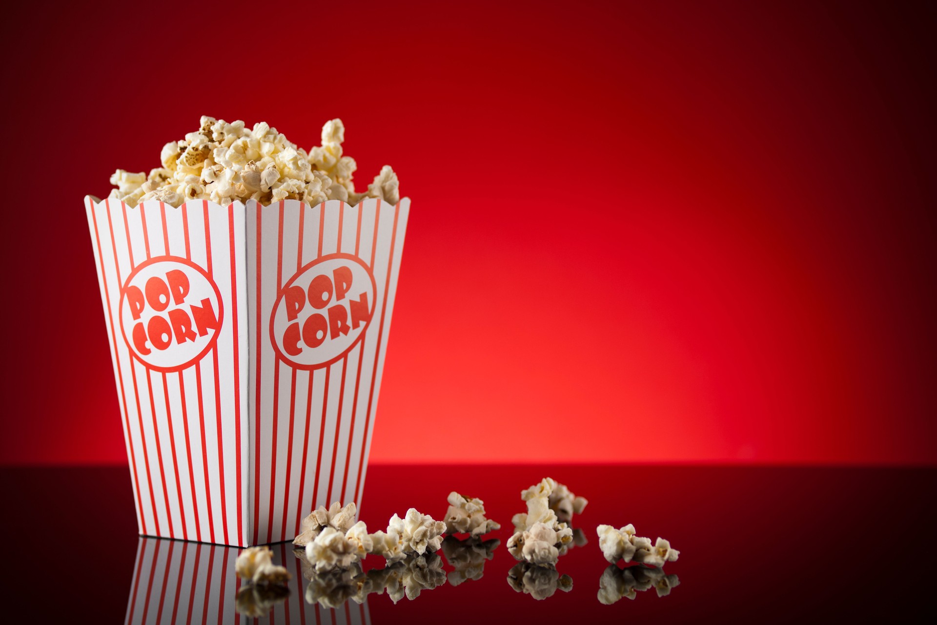 Box of popcorn on reflective surface and red background