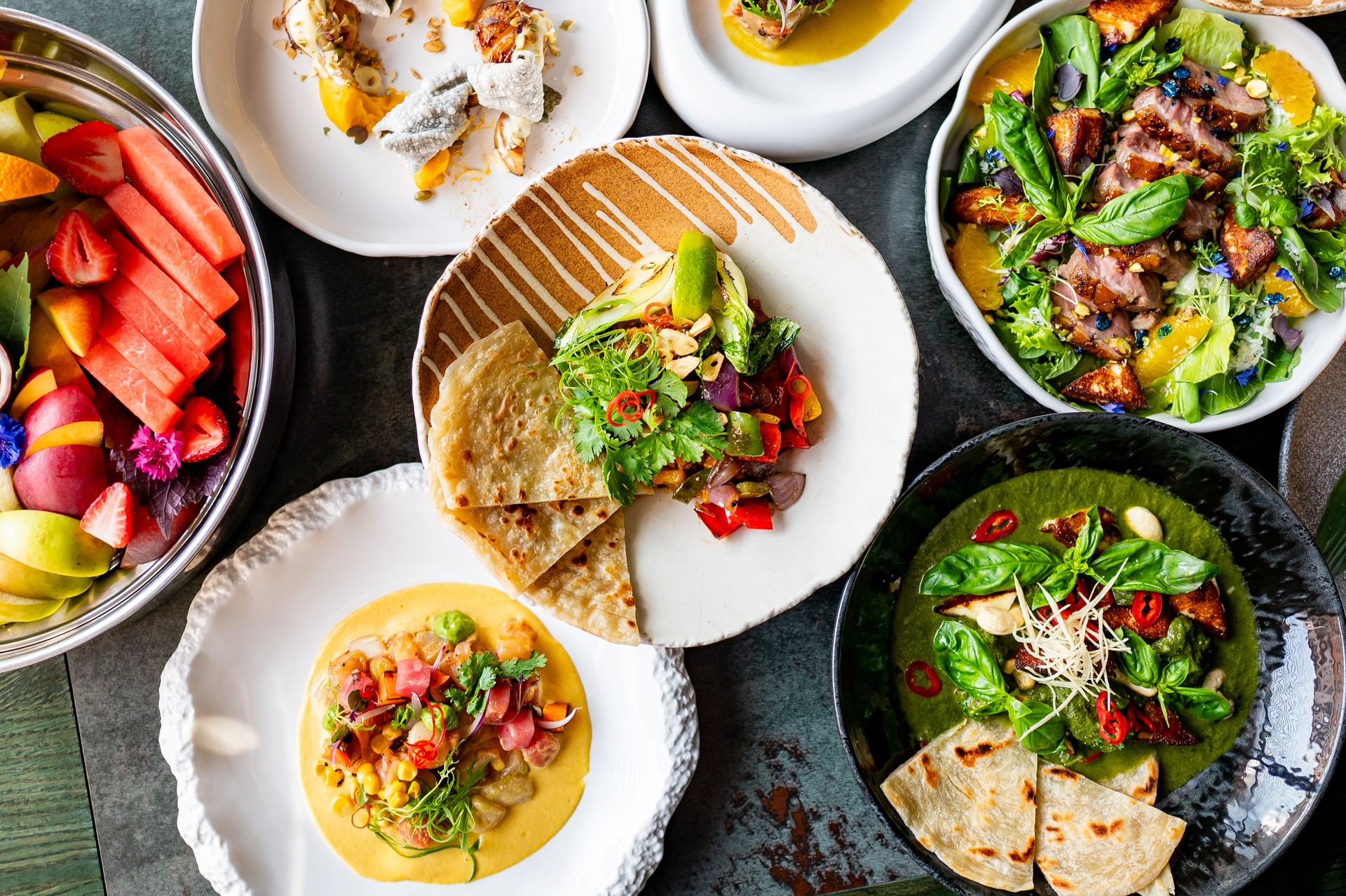 A vibrant display of gourmet dishes including fresh salads, grilled vegetables, and artisan bread on a modern table setting. Perfect for culinary, lifestyle, or food-related themes.