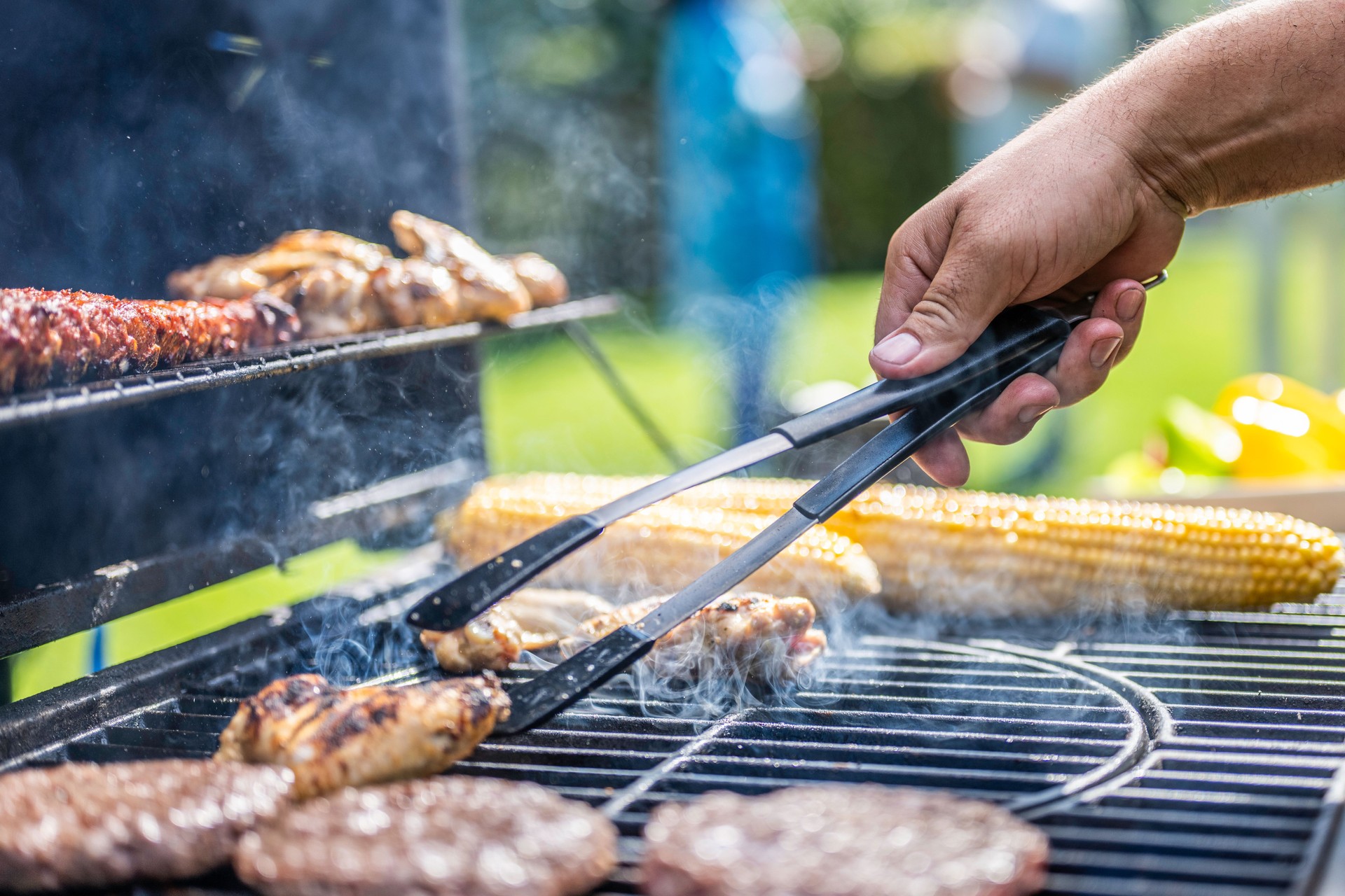 Chicken meat on grill being flipped with tongs